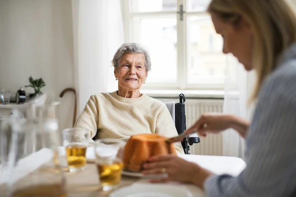 Female daughter sitting at a table with her elderly female mother
